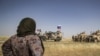 A Syrian woman looks at U.S. and Russian soldiers in the northeastern Syrian town of Malikiyah at the border with Turkey, June 3, 2020. 