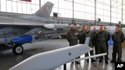 A group of Polish Air Force pilots stand next to a F-16 fighter jet and a model of a JASSM missile as they attend a contract signing ceremony of 40 Lockheed Martin’s joint air-to-surface standoff missiles (JASSM), as well as F-16 fighter plane…