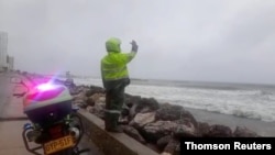 Полицейский предупреждает людей, зашедших в воду, несмотря на запрет в связи с приближающимся ураганом. Картахена, Колумбия.